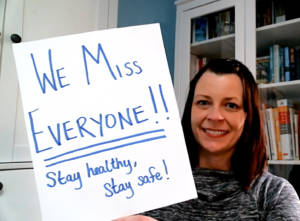 Julie holding "We Miss Everyone!!" Sign